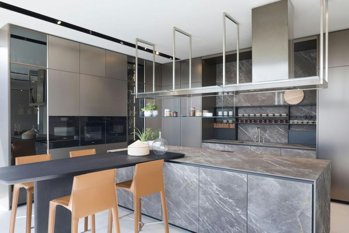 Modern kitchen island clad in grey veined stone with a matching backsplash