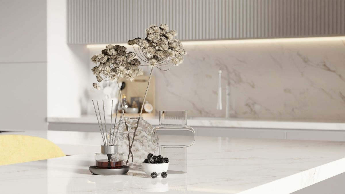White countertop and full-height backsplash with soft warm veining in a bright modern kitchen
