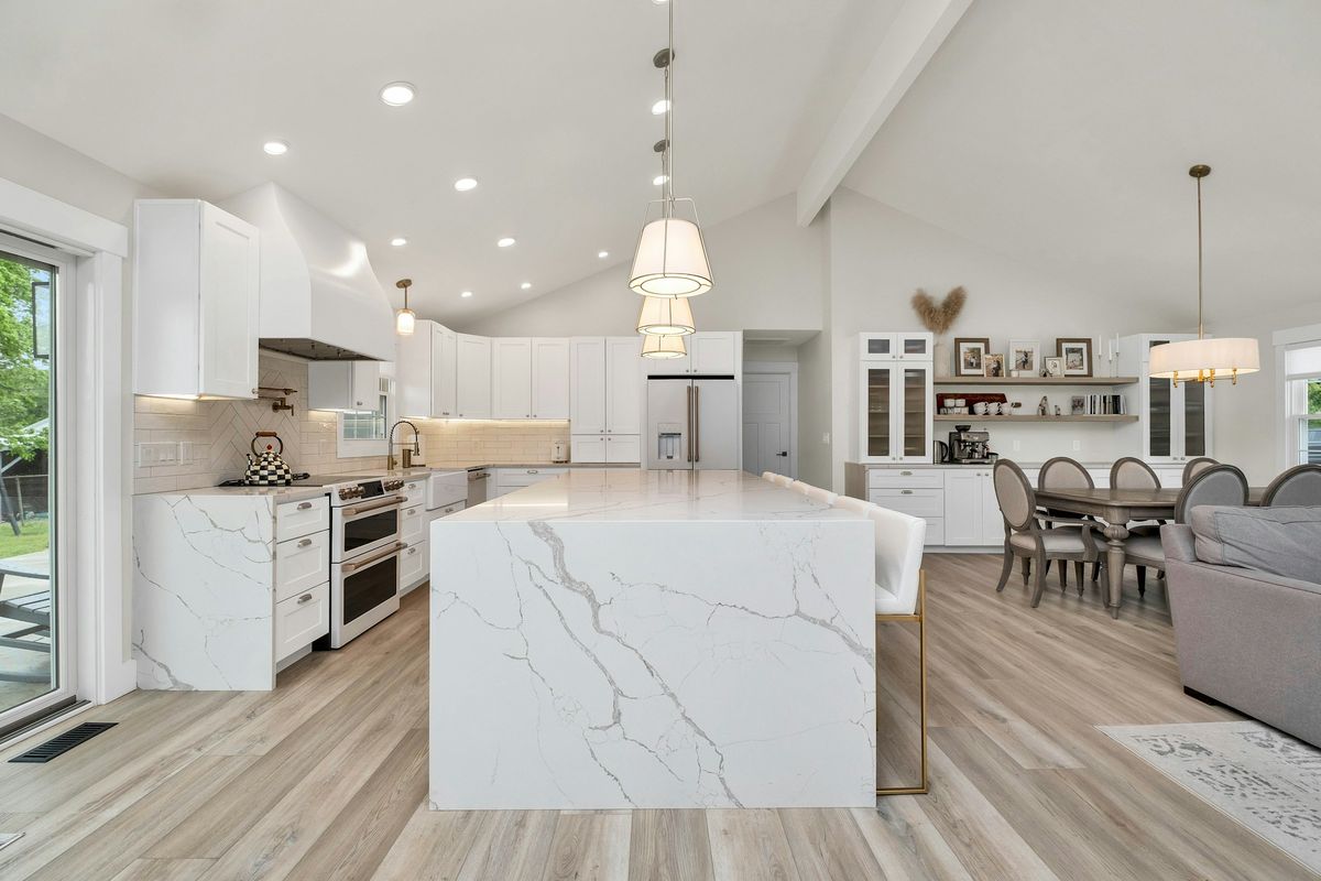 White waterfall-edge island with grey veining in a bright open-plan kitchen